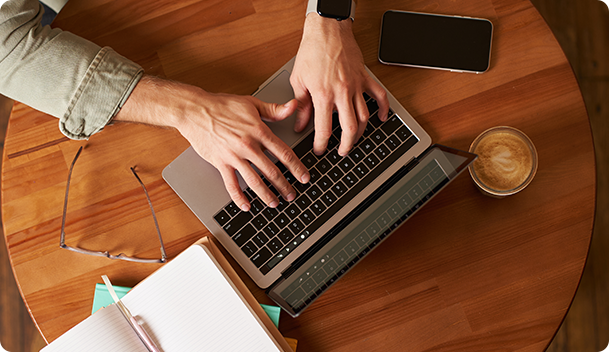 Person working on a laptop at a wooden desk